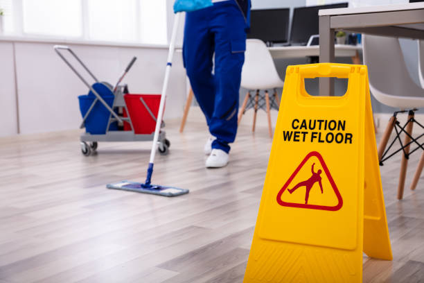 Male janitor with mop cleaning the floor, with caution site wet floor