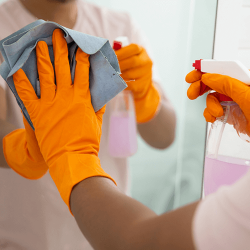 housekeeper is cleaning a mirror with a spray bottle