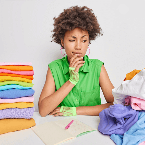 woman with a worried expression surrounded by unfolded and folded clothes