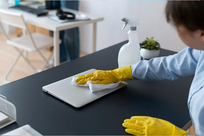 female staff wiping desk and laptop