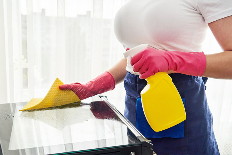 Young woman wearing gloves while cleaning the table