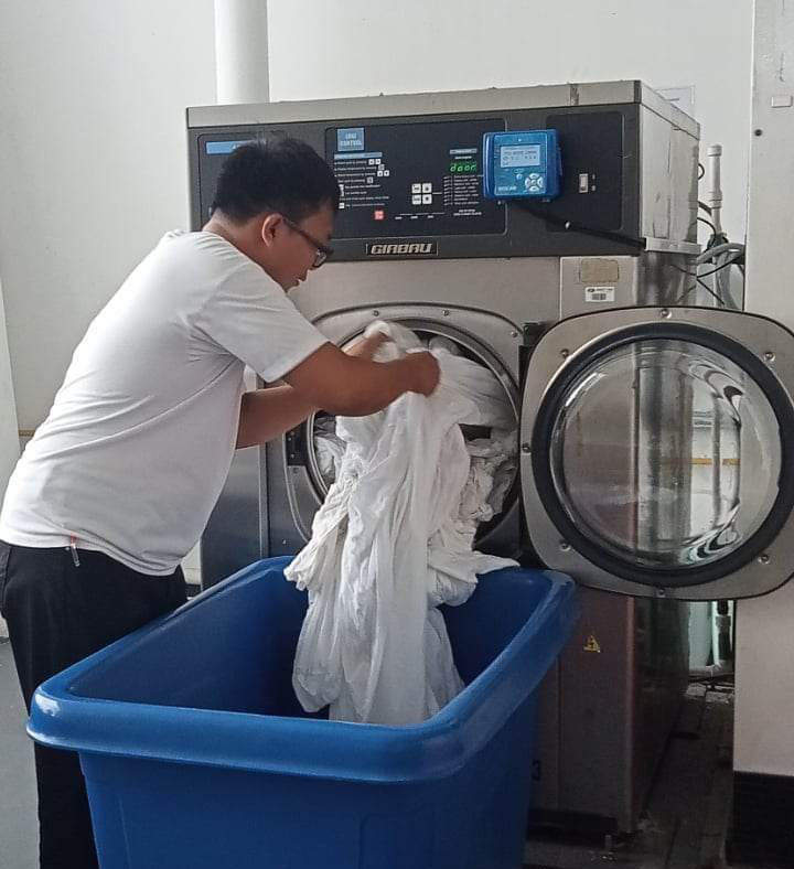 laundry workers are placing clothes into the laundry machine