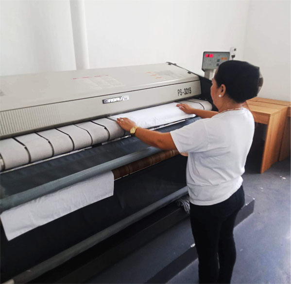 laundry staff is ironing clothes using a machine