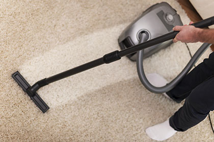 man using a vacuum cleaner to clean the carpet