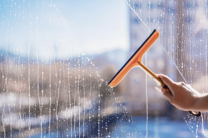 woman is cleaning a window with a cleaning solution