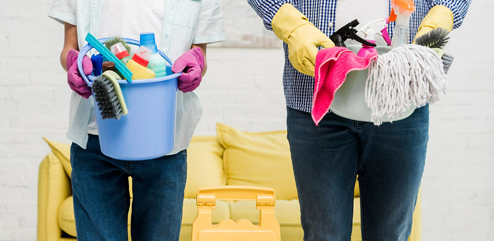 Two cleaners holding buckets filled with cleaning tools
