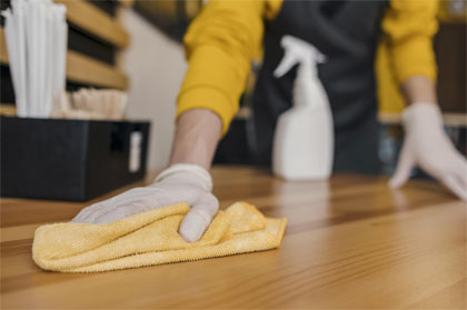 housekeeper cleaning table while wearing latex glove